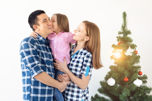 Concepto de vacaciones, regalos y árbol de Navidad: familia pequeña que tiene tiempo feliz juntos en Navidad