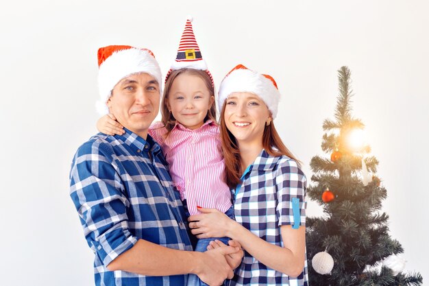 Concepto de vacaciones, regalos y árbol de Navidad: familia pequeña que tiene tiempo feliz juntos en Navidad