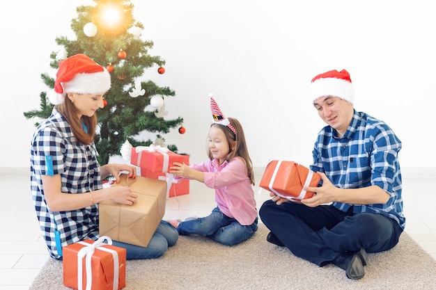 Concepto de vacaciones y regalos - Retrato de una familia feliz abriendo regalos en Navidad.