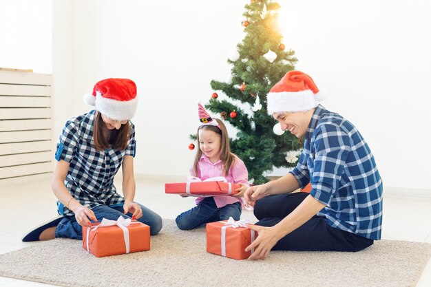 Concepto de vacaciones y regalos - Retrato de una familia feliz abriendo regalos en Navidad.