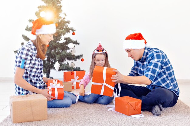 Concepto de vacaciones y regalos - Retrato de una familia feliz abriendo regalos en Navidad.