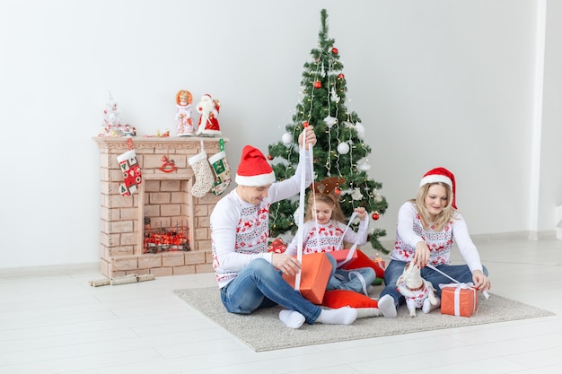 Concepto de vacaciones y regalos - Retrato de una familia feliz abriendo regalos en Navidad.