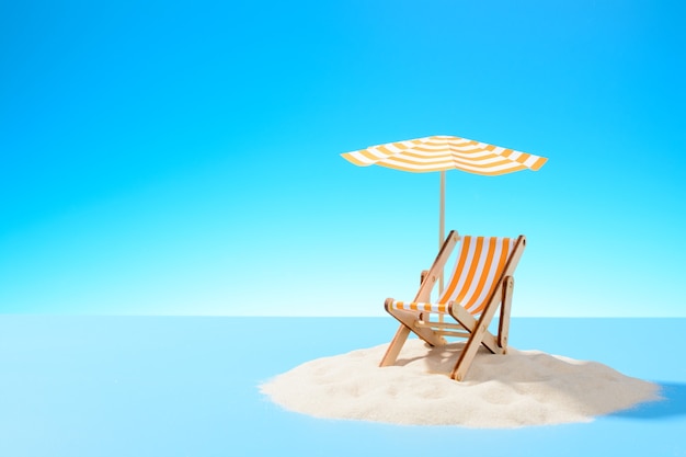 El concepto de unas vacaciones tropicales. Una tumbona bajo una sombrilla en la isla de arena. Cielo con espacio de copia