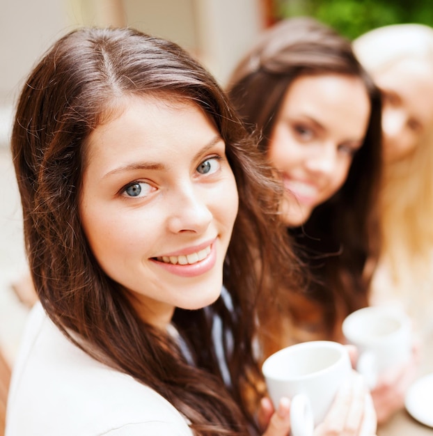 concepto de vacaciones y turismo - chicas guapas tomando café en la cafetería