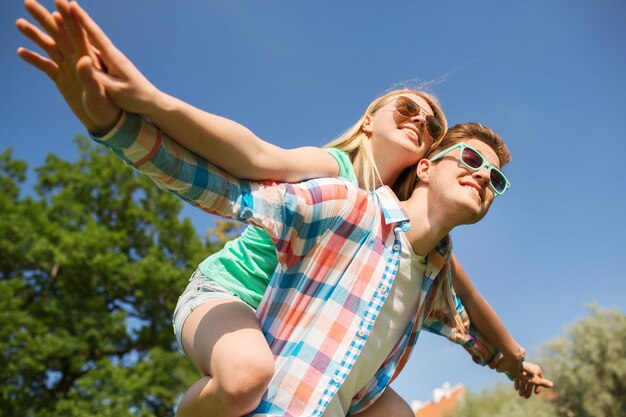 concepto de vacaciones, vacaciones, amor y amistad - pareja sonriente divirtiéndose en el parque