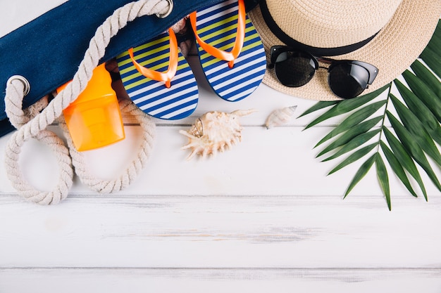 Concepto de vacaciones de vacaciones de verano. Bolsa de playa y accesorios en mesa de madera blanca. Vista superior y endecha plana.