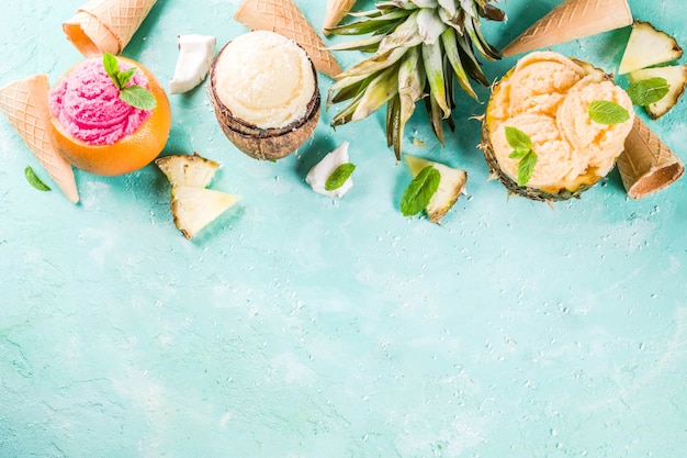 Concepto de vacaciones de vacaciones de verano, establezca varios sorbetes de helado tropical, jugos congelados en piña, pomelo y coco, concreto azul claro