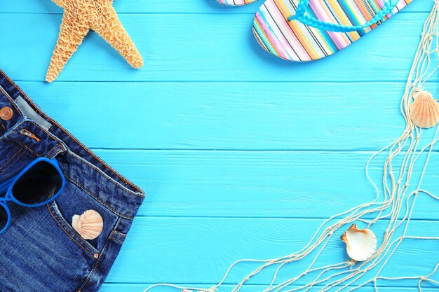 Foto concepto de vacaciones de verano composición con chanclas y jeans sobre fondo de madera de color