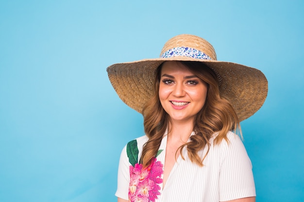 Concepto de vacaciones, verano, moda y personas - Chica con sombrero de paja de ropa de moda. Retrato de mujer encantadora sobre fondo azul con copia espacio vacío.