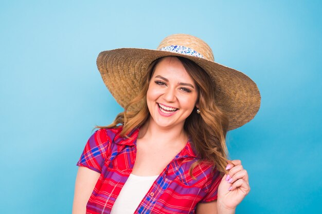 Concepto de vacaciones, verano, moda y personas - Chica con sombrero de paja de ropa de moda. Retrato de mujer encantadora sobre fondo azul con copia espacio vacío.