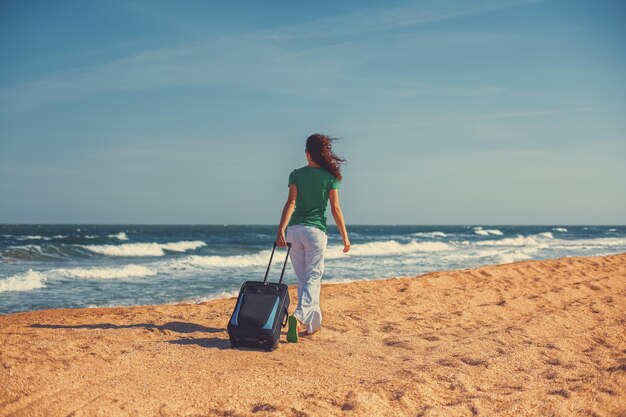 Concepto de vacaciones verano Mujer joven con bolsa de viaje caminando por la playa