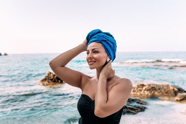 Concepto de vacaciones de verano Mujer de moda joven en la orilla de mar rocosa.