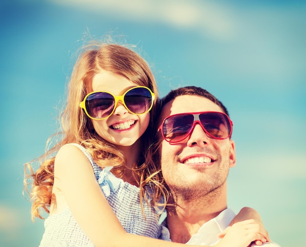 concepto de vacaciones de verano, niños y personas - feliz padre e hijo con gafas de sol sobre el cielo azul