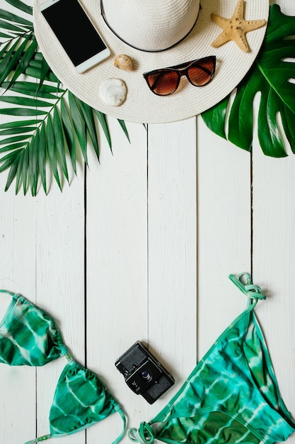 Concepto de vacaciones de verano con traje de bikini y accesorios sobre fondo blanco de mesa de madera