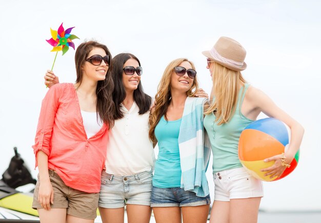 Foto concepto de vacaciones de verano, vacaciones y actividades en la playa - chicas sonrientes en sombras divirtiéndose en la playa