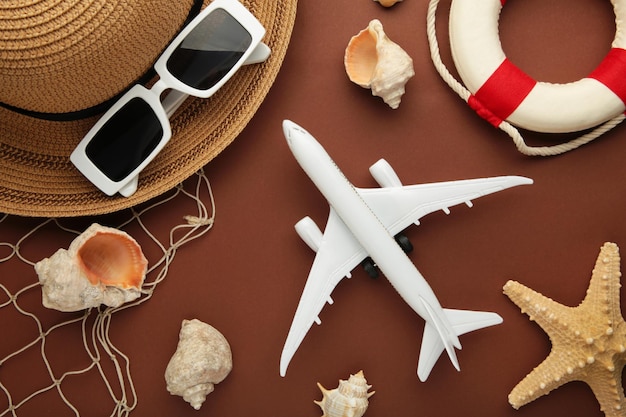 Concepto de vacaciones de viaje Sombrero con gafas de sol y conchas marinas sobre fondo marrón Espacio para texto Foto vertical