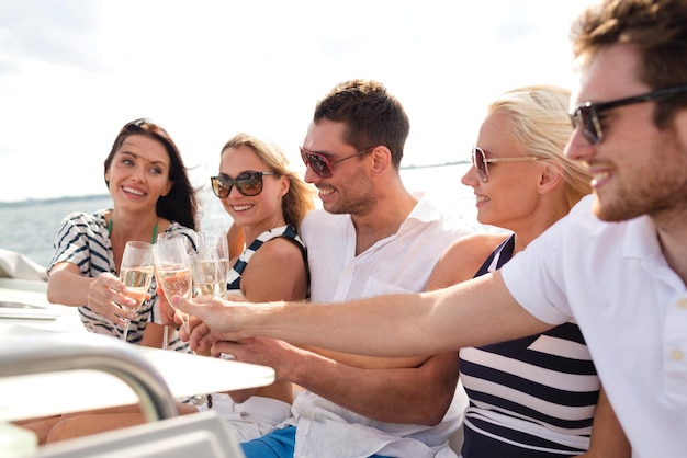 concepto de vacaciones, viajes, mar, amistad y personas - amigos sonrientes con copas de champán en yate