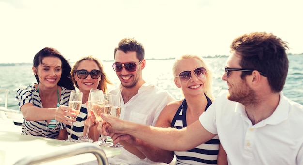 concepto de vacaciones, viajes, mar, amistad y personas - amigos sonrientes con copas de champán en yate