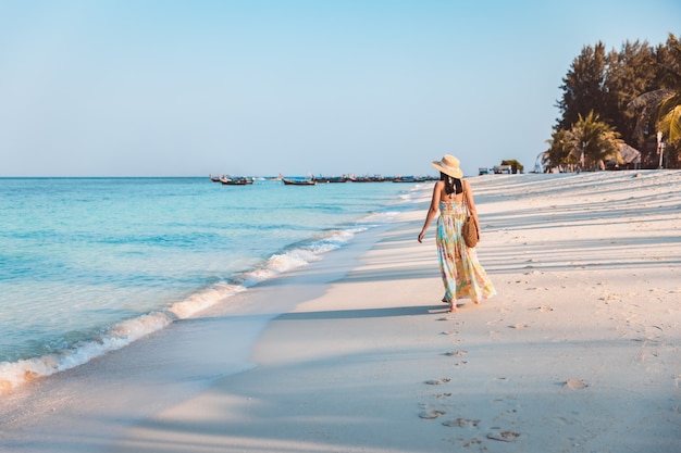Foto concepto de vacaciones de viajes de verano, feliz viajero mujer asiática con vestido relajarse y hacer turismo en la playa por la noche en koh lipe, satun, tailandia