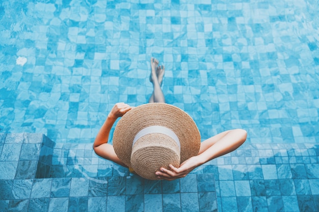 Concepto de vacaciones de viajes de verano, mujer asiática feliz viajero con sombrero y bikini relajarse en el lujoso hotel resort con piscina infinita en el día en Phuket, Tailandia