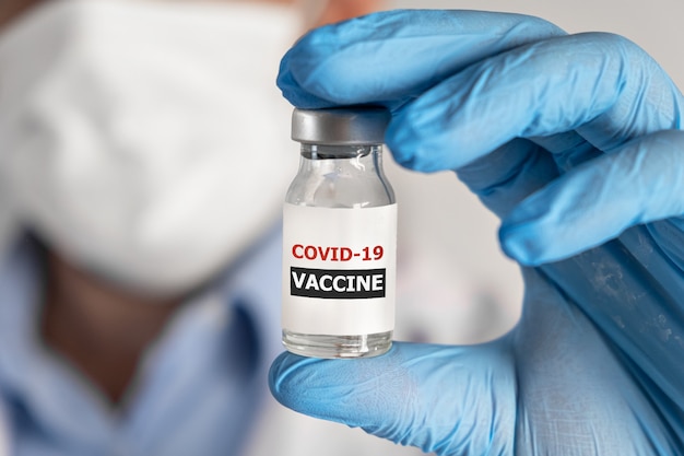 Concepto de vacunación contra el coronavirus de Covid en la mano del médico, frasco de vacuna de vidrio, ampolla, bata blanca y