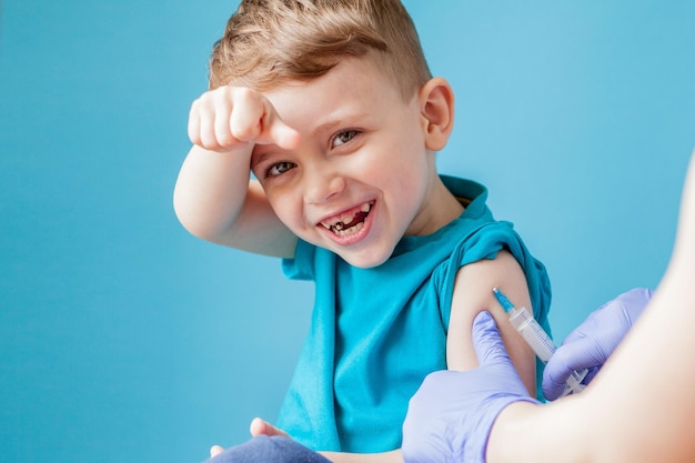 Concepto de vacunación Doctora vacunando a un niño lindo sobre fondo azul de cerca