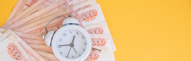 El concepto de valor temporal del dinero reloj analógico en el billete de rublo ruso que representa recibir dinero hoy puede estar preparado para aumentar el valor futuro mediante la inversión y la obtención de intereses durante un período de tiempo