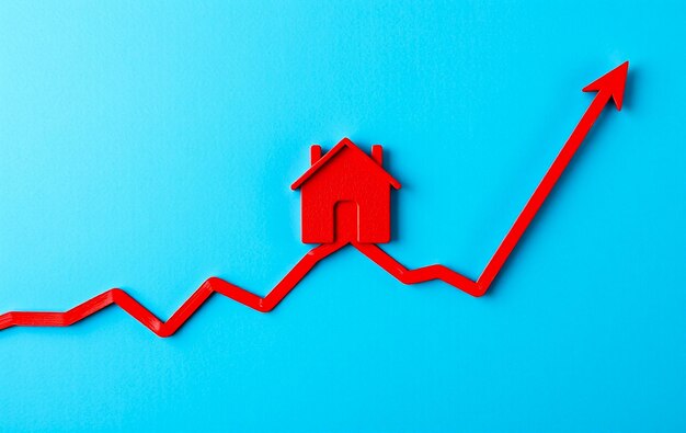 Concepto de valores de propiedad en aumento con diseño de casa roja en línea roja ascendente gráfico en fondo azul abstracto