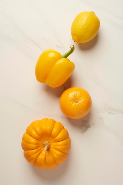 Concepto de vegetales algunos vegetales amarillos y naranjas ordenados juntos en la mesa de baldosas blancas.