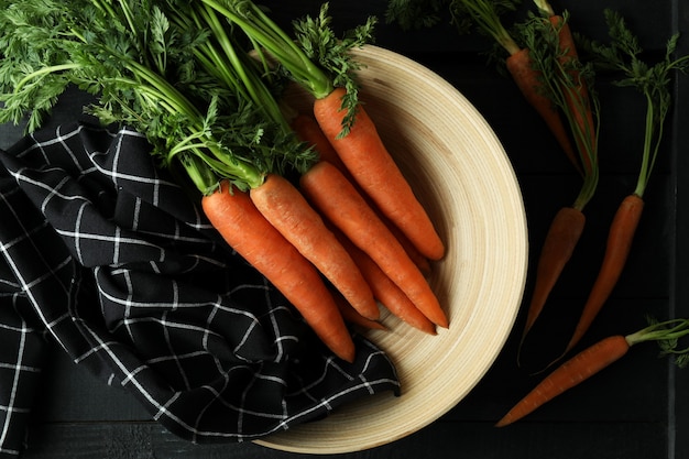 Concepto de vegetales frescos con zanahoria en mesa de madera oscura.