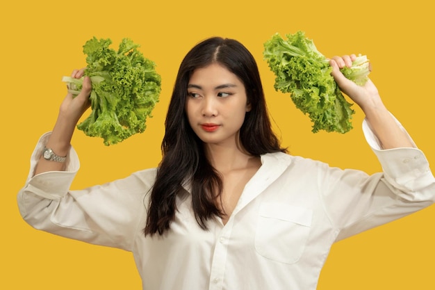 Concepto vegetariano Mujer sana con camisa blanca sostenga lechuga fresca sobre fondo amarillo aislado