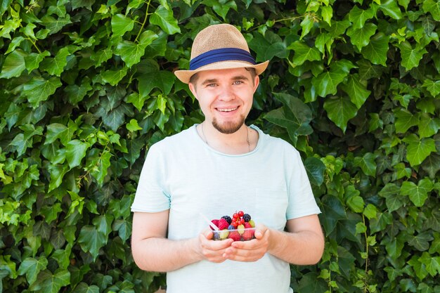 Concepto de vegetarianos, alimentos crudos y dietas - Hombre guapo con frutas y bayas