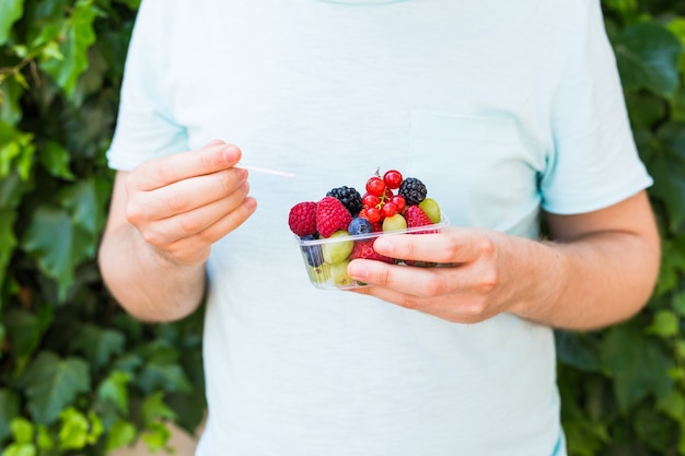 Concepto de vegetarianos, alimentos crudos y dietas - primer plano del hombre mantenga frutas y bayas.