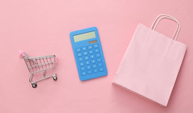 Concepto de venta Bolsa de compras con calculadora carrito de compras sobre fondo rosa Vista superior