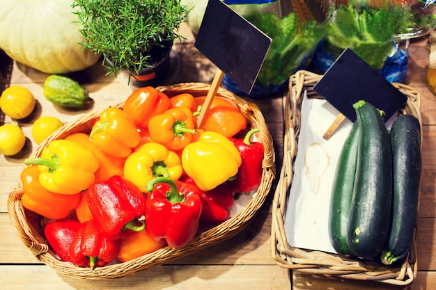 concepto de venta, compras y alimentos ecológicos: verduras maduras en cestas con placas de identificación en el mercado de comestibles