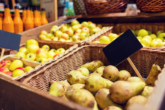 concepto de venta, compras, comida vegetariana y ecológica - frutas en cestas con placas de identificación en el mercado biológico