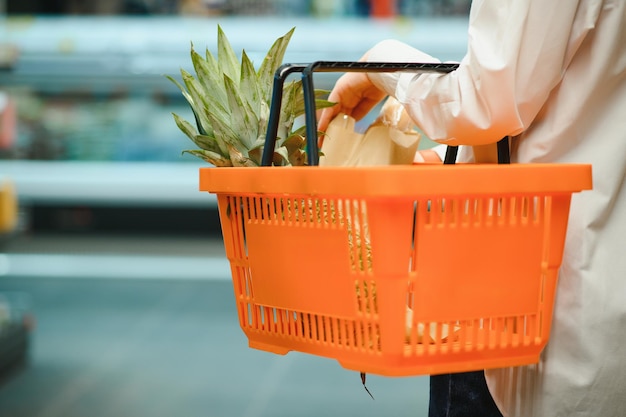 Concepto de venta, compras, consumismo y personas - mujer con canasta de alimentos en la tienda de comestibles o supermercado