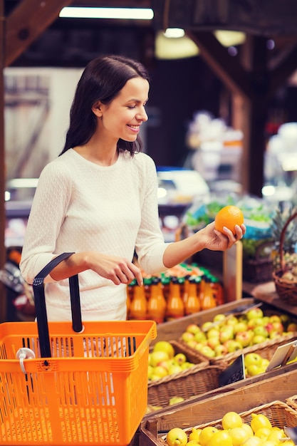 Foto concepto de venta, compras, consumismo y personas - mujer joven feliz con canasta de alimentos en el mercado