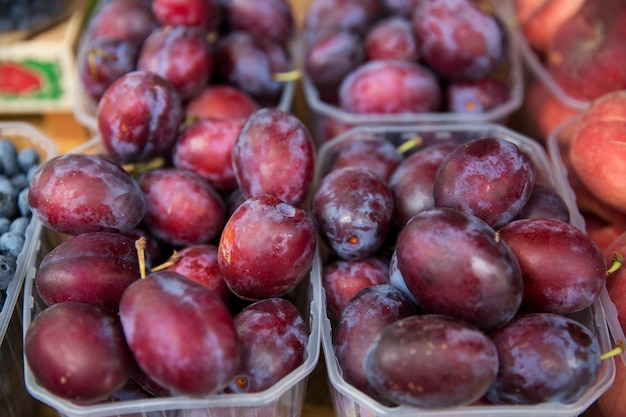 concepto de venta, cosecha, alimentos, frutas y agricultura - cierre de ciruelas satsuma en cajas de plástico en el mercado callejero