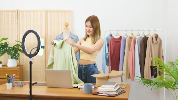 Concepto de venta en línea Diseñador de moda que muestra ropa para la venta en transmisión en vivo en la oficina en casa