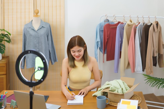 Concepto de venta en línea Diseñador de moda tomando notas pedidos en línea en un cuaderno después de la transmisión en vivo
