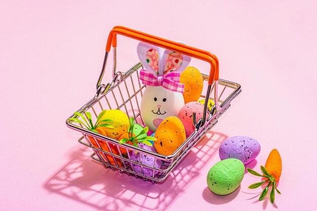 Concepto de venta de Pascua Cesta de la compra con símbolos festivos huevos de conejo pájaro y decoración tradicional Diseño pastel moda dura luz oscura sombra rosa fondo copia espacio