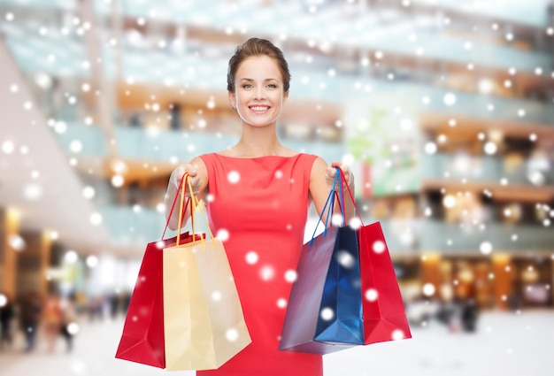 concepto de venta, regalos, vacaciones y personas - mujer sonriente con bolsas coloridas sobre el fondo del centro comercial