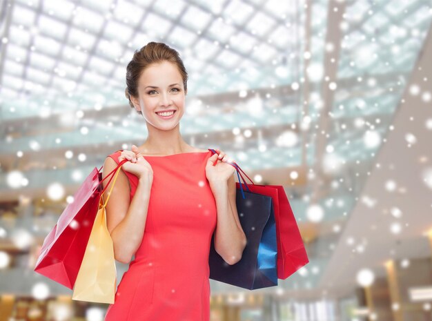 concepto de venta, regalos, vacaciones y personas - mujer sonriente con bolsas coloridas sobre el fondo del centro comercial