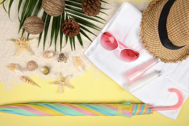 Concepto de verano y accesorios (conchas, estrellas de mar, hoja de coco) con playa de arena.