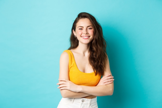 Concepto de verano y estilo de vida hermosa mujer joven en top corto amarillo con los brazos cruzados sobre el pecho ...