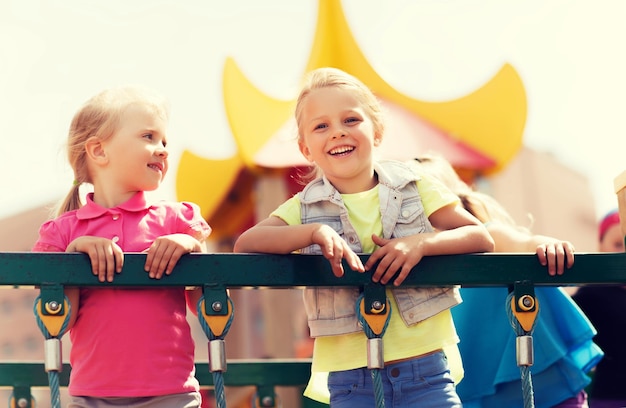 concepto de verano, infancia, ocio, amistad y personas - niñas felices en el marco de escalada del parque infantil