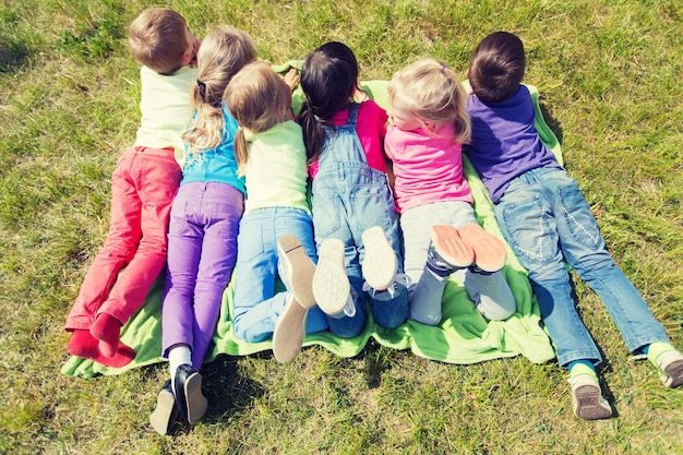 concepto de verano, infancia, ocio y personas - grupo de niños felices acostados en una manta o cubierta al aire libre