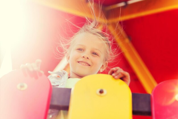 concepto de verano, infancia, ocio y personas - niña feliz en el marco de escalada del patio