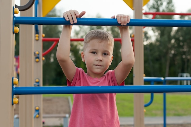 Concepto de verano, infancia, ocio y personas: niño feliz en el patio de recreo